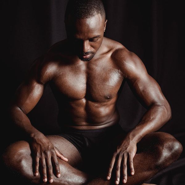 Man sitting in a focused, meditative posture against a dark background.